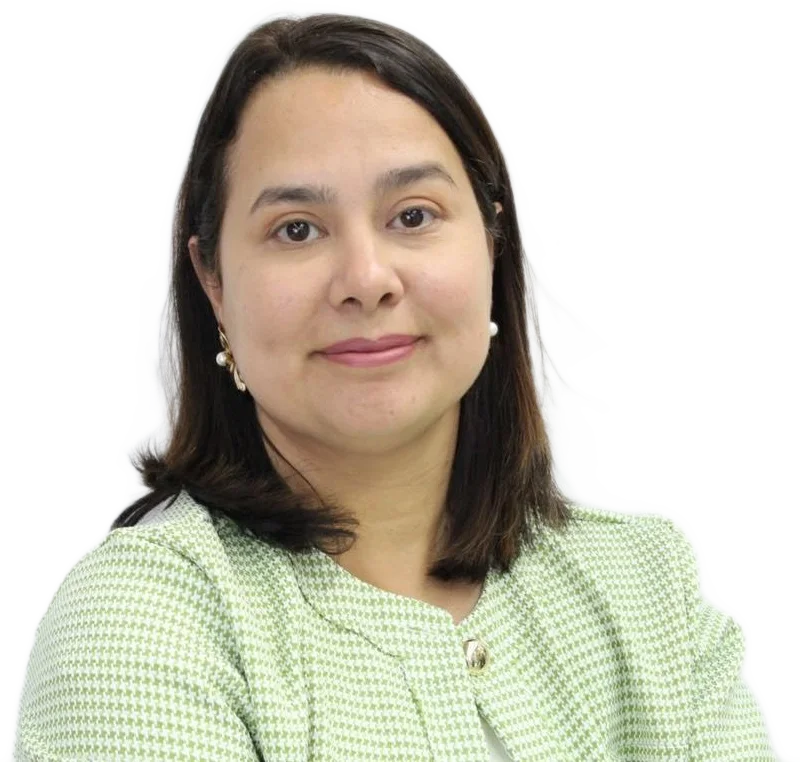 Dra. Sueleny Vinson, de blazer pied-de-poule verde-claro e brincos de pérola, olhando para a frente com um sorriso contido.